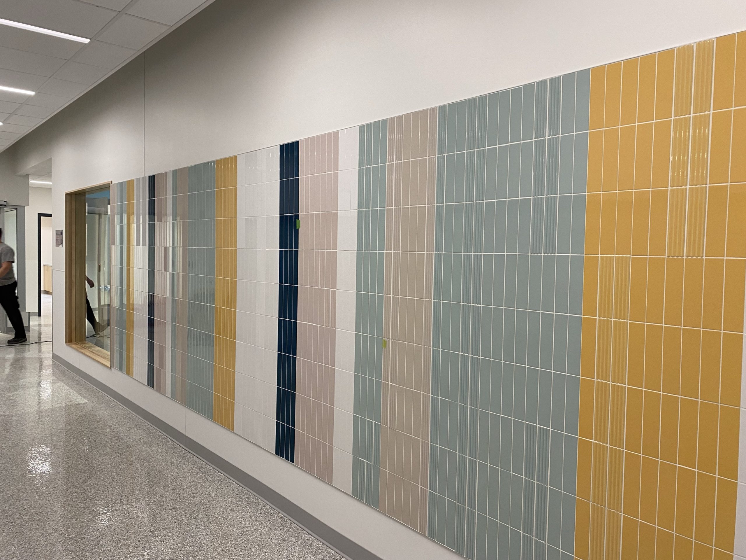 Murale céramique. Texturé pour le sensoriel des élèves. C’est écrit École René St-Pierre 2025 en brail. Par les tuiles tecturées